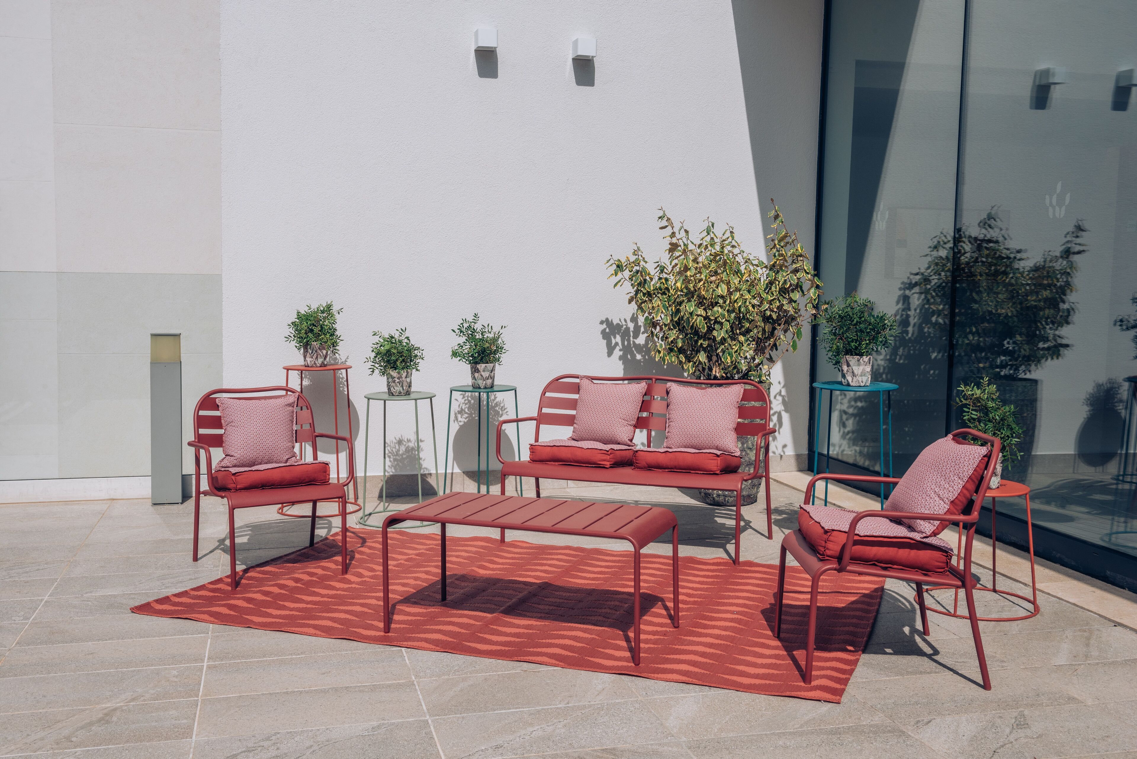 Un área de descanso al aire libre con muebles metálicos y plantas en macetas.