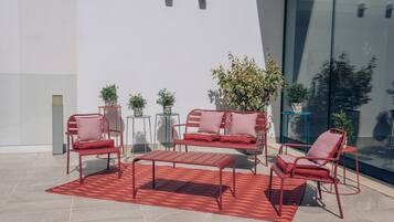 Un área de descanso al aire libre con muebles metálicos y plantas en macetas.