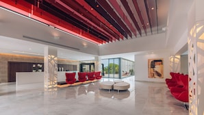 A spacious lobby with a modern design, featuring a reception desk, seating area, and a large window offering a view of the outdoors. - Iberostar Waves Cala Millor -Adults Only (Sant Llorenc des Cardassar)