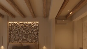 Un dormitorio con pared de piedra, una cama, una silla y una mesita.