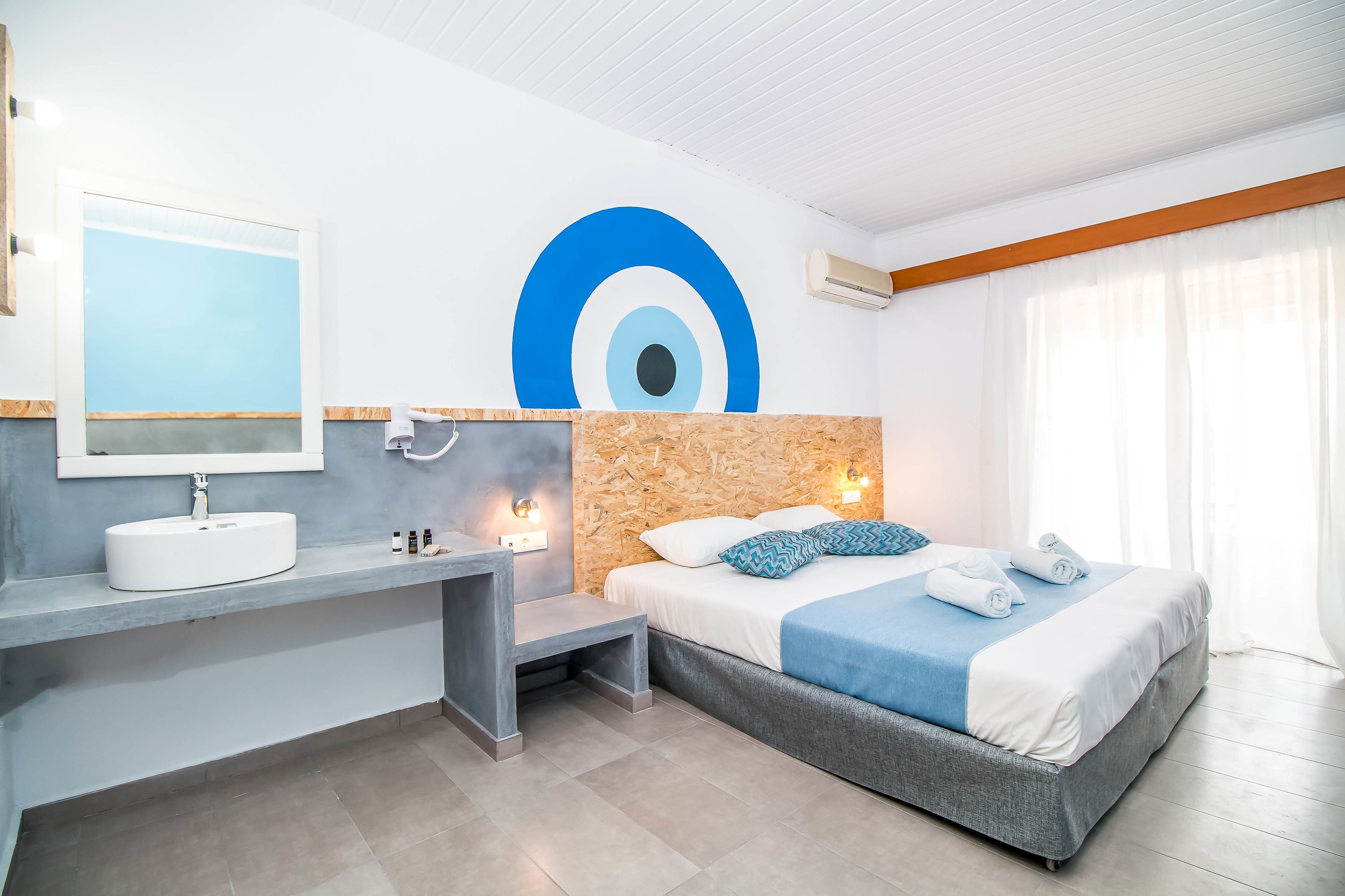 Quarto de hotel moderno com uma cama grande, toucador embutido e um grande mural na parede.