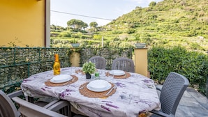 Tavolo apparecchiato all'aperto con vista su un giardino collinare.