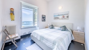Una camera da letto con un letto grande, una sedia, un termosifone, una finestra e una parete con un quadro.