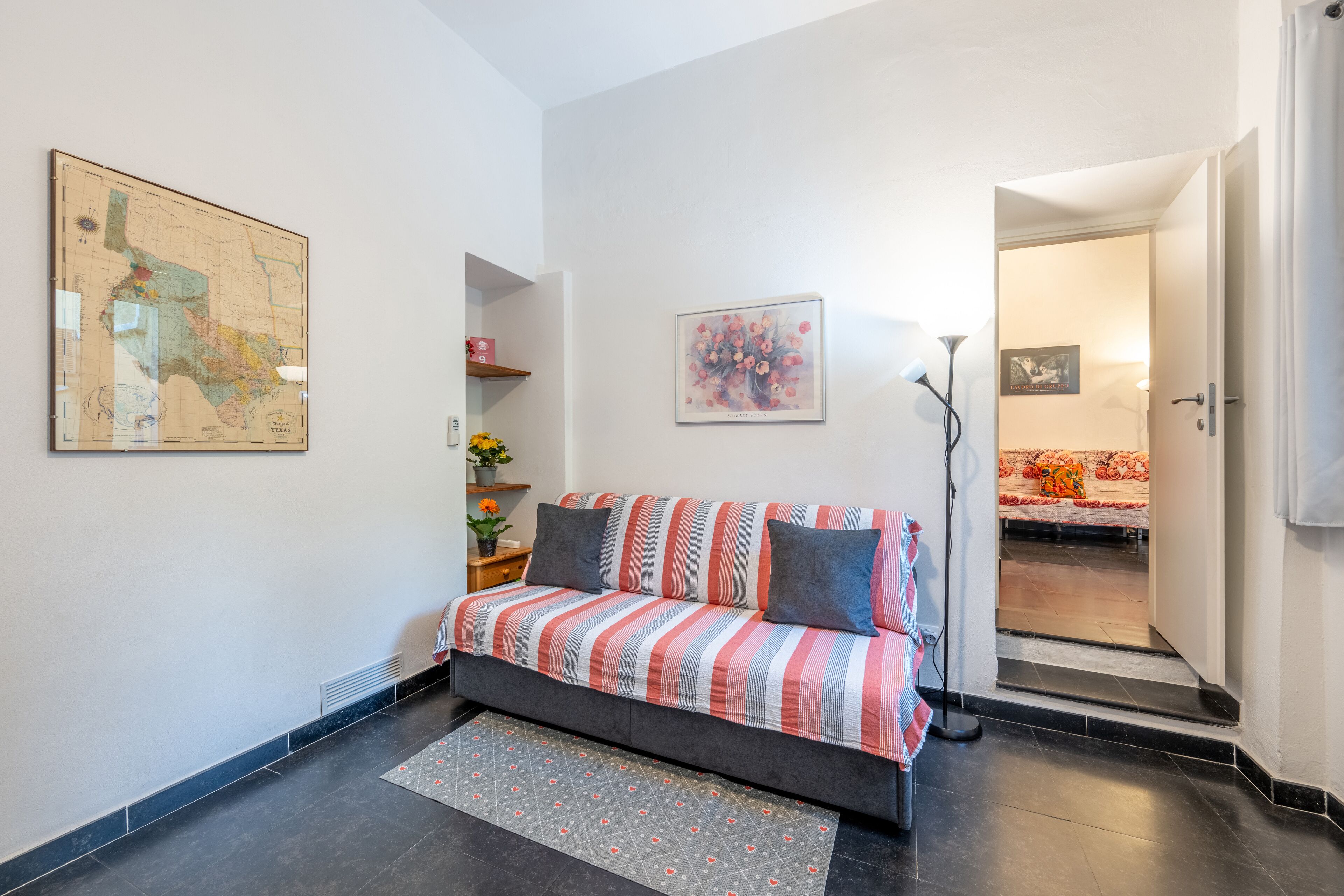 Un salon moderne avec un canapé, une carte accrochée au mur et une porte-fenêtre donnant sur une autre pièce.