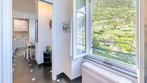 Una cucina moderna con mobili bianchi, un'area pranzo con tavolo e sedie e un'ampia finestra che si affaccia su un paesaggio verdeggiante.