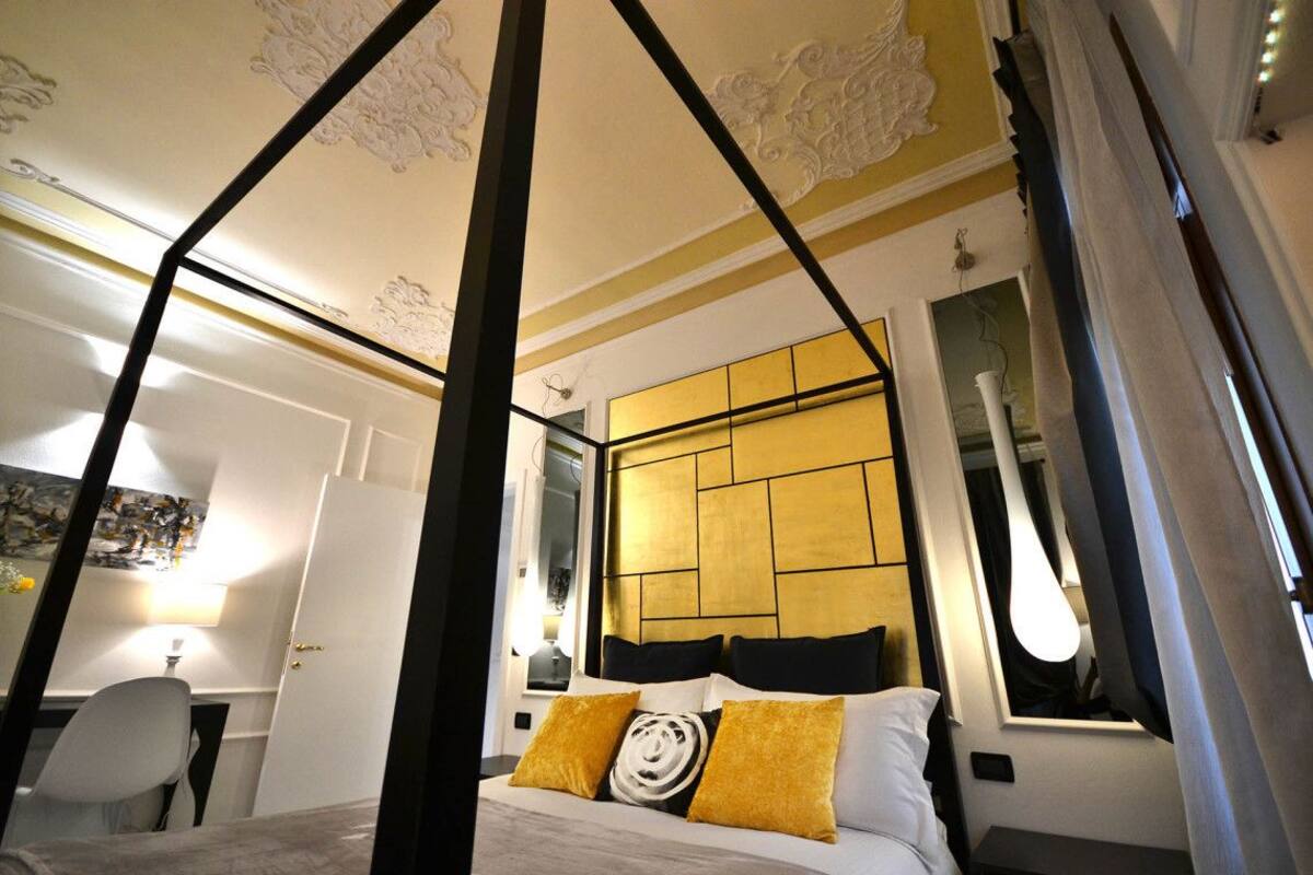 A modern bedroom with a canopy bed, a large mirror, and a view of the city.