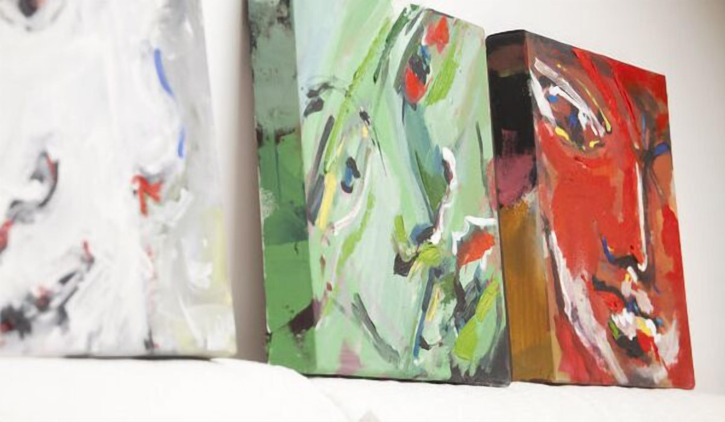 Three abstract paintings on a white wall.