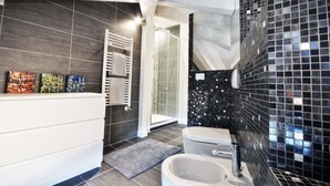 A modern bathroom with dark tiled walls, a white vanity, a glass shower enclosure, and a mosaic tile backsplash. - Venice Art Design Bed & Breakfast (Mestre)