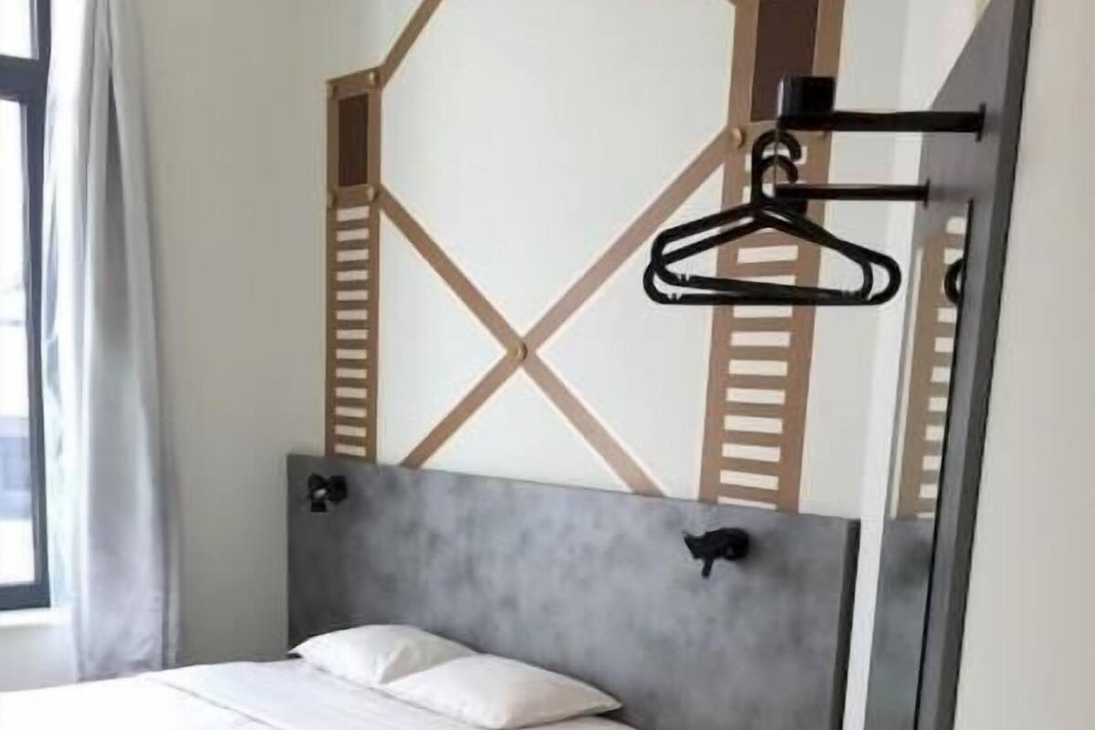 Een moderne slaapkamer met een bed, nachtkastje en een uniek geometrisch muurontwerp.