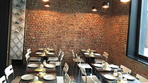 Een restaurant met bakstenen muren, meerdere tafels en hangende lampen.