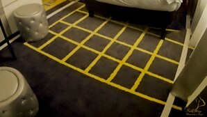 Een hotelkamer met een bed, hoofdeinde, een wandlamp en een vloer met patroon.