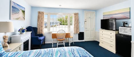 A hotel room with a bed, a desk, a chair, a television, a microwave, and a dresser.