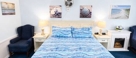 Une chambre d’hôtel comprenant un lit, deux tables de chevet, une chaise, une cheminée et des œuvres d’art murales.