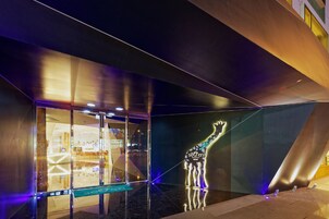 A modern building with a glass facade, a giraffe sculpture, and a sign reading "se7en".