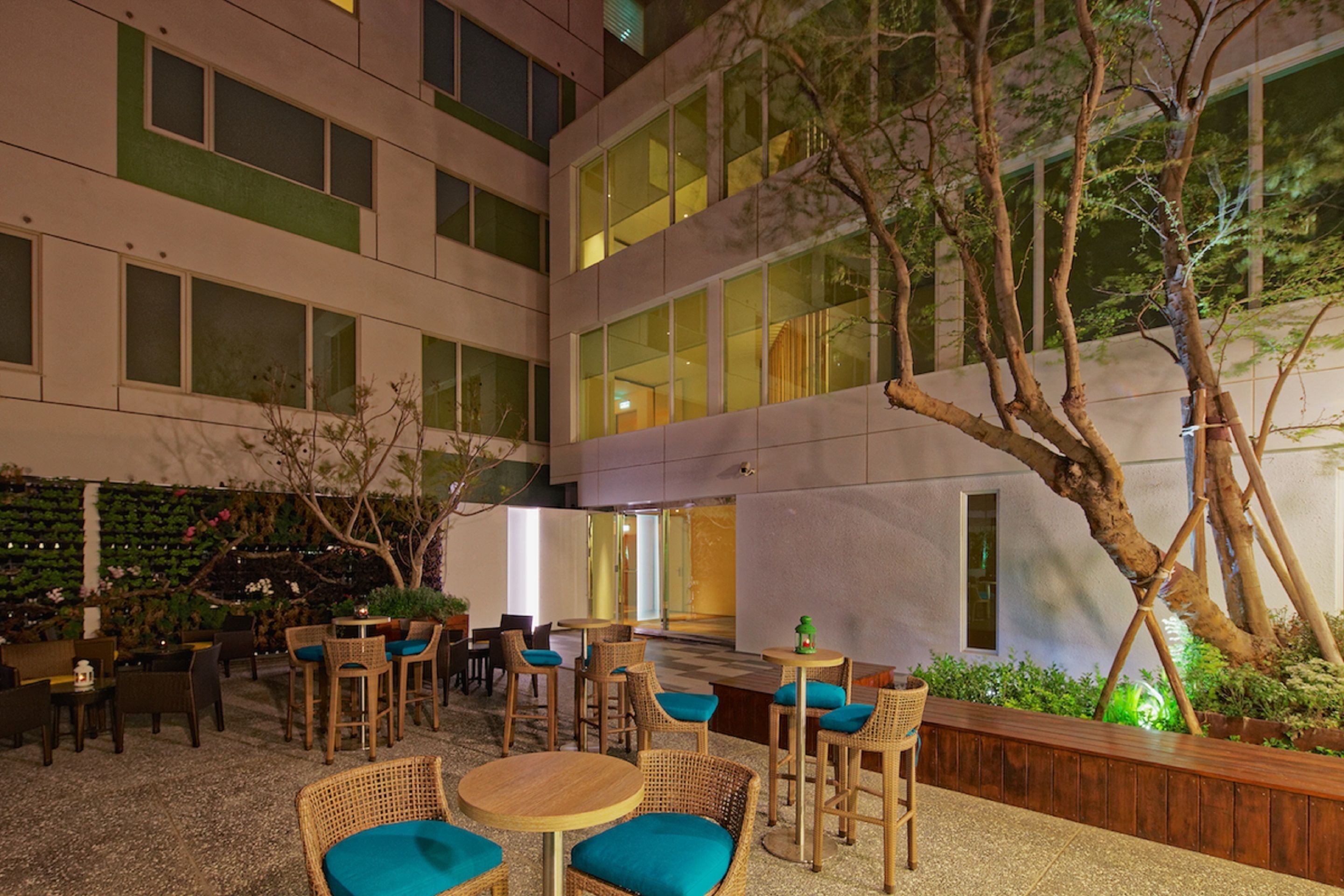An outdoor seating area with wicker furniture and a view of a building with large windows.