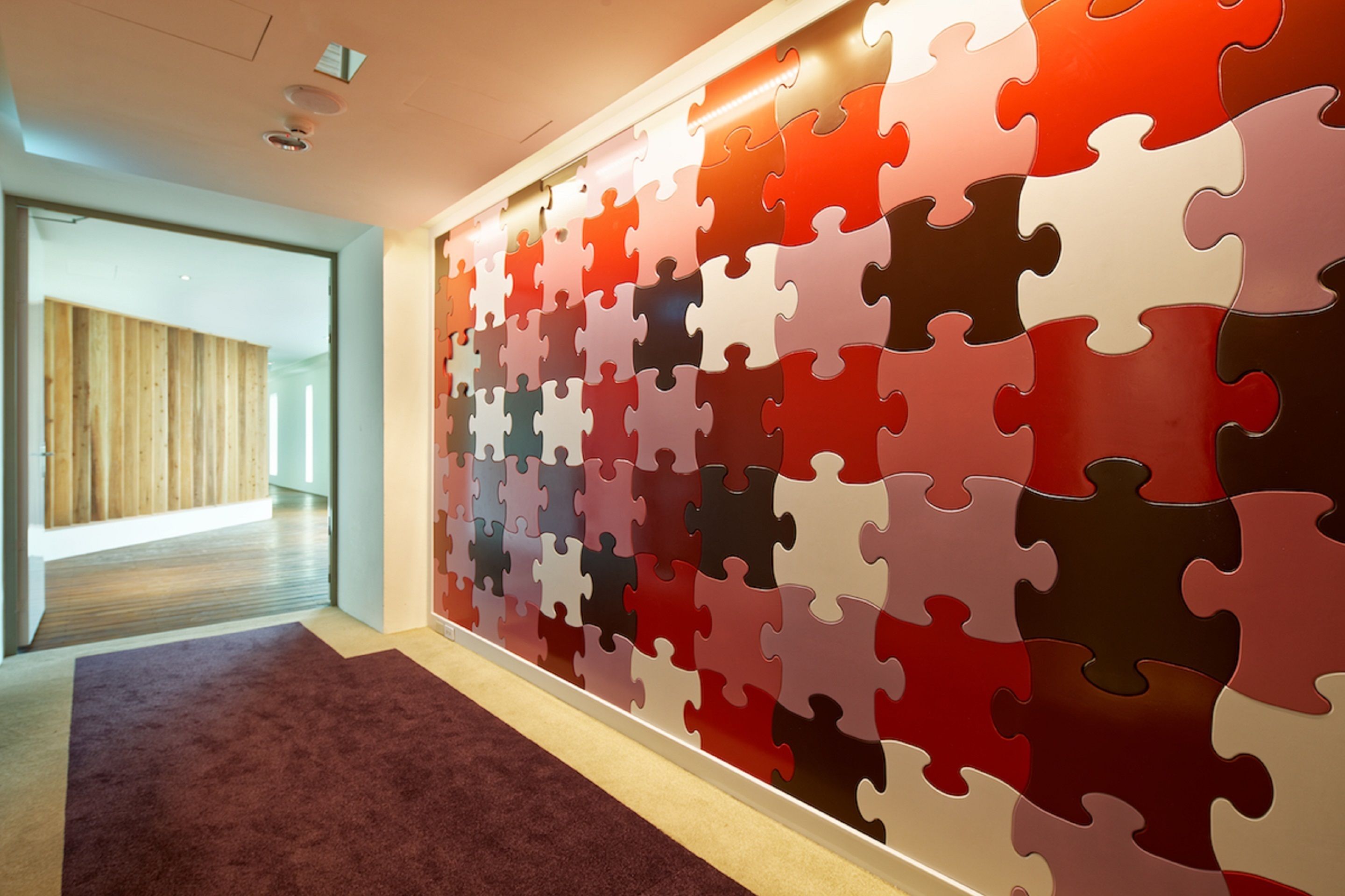 Ein Flur mit einer Wand, die mit bunten Puzzleteilen bedeckt ist.