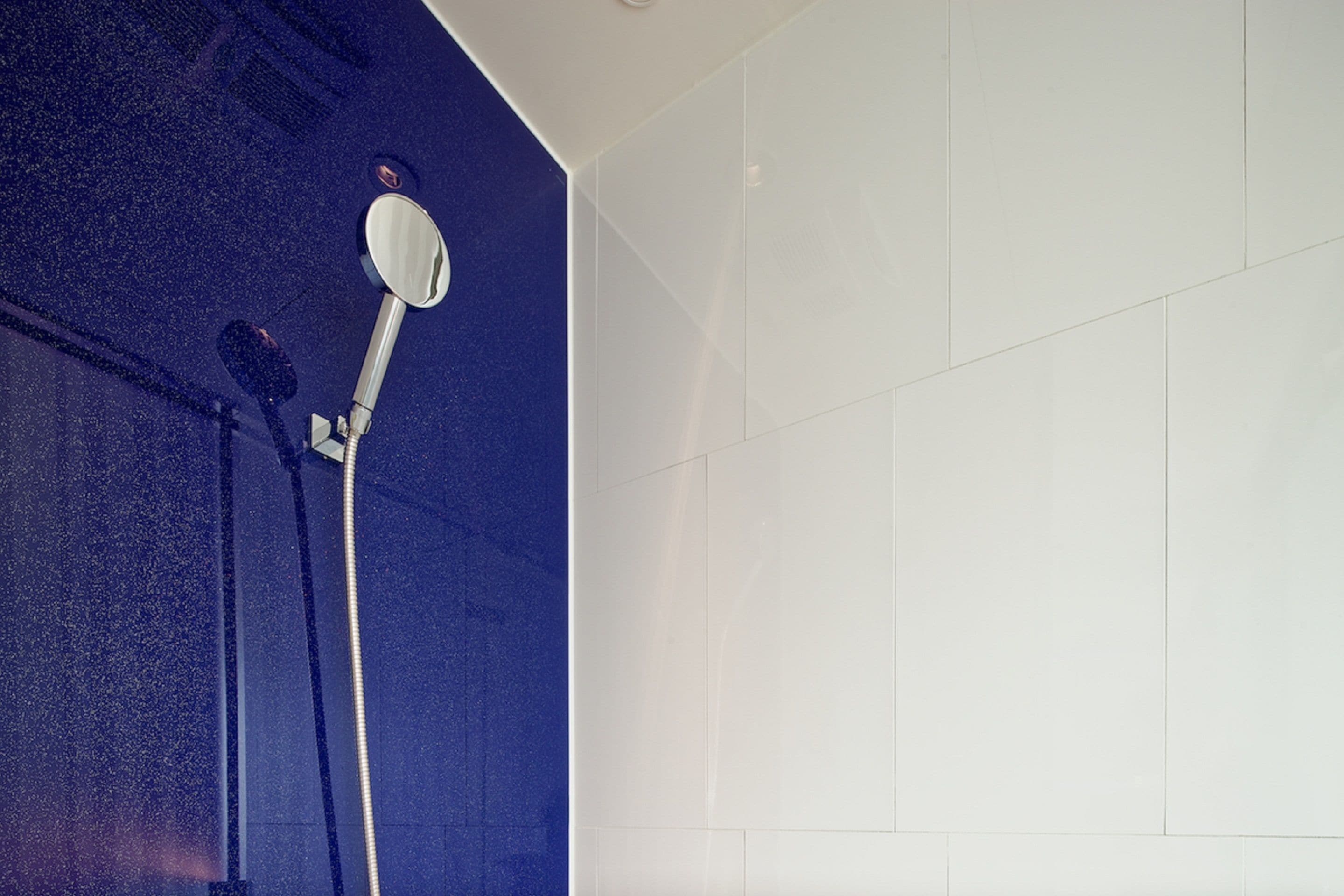 Ein Badezimmer mit Dusche, weißen Fliesen und einer blauen Akzentwand.