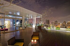 A modern outdoor lounge area with wooden flooring, seating, and a glass railing overlooking a cityscape. - Hotel 7 Taichung (Taichung)