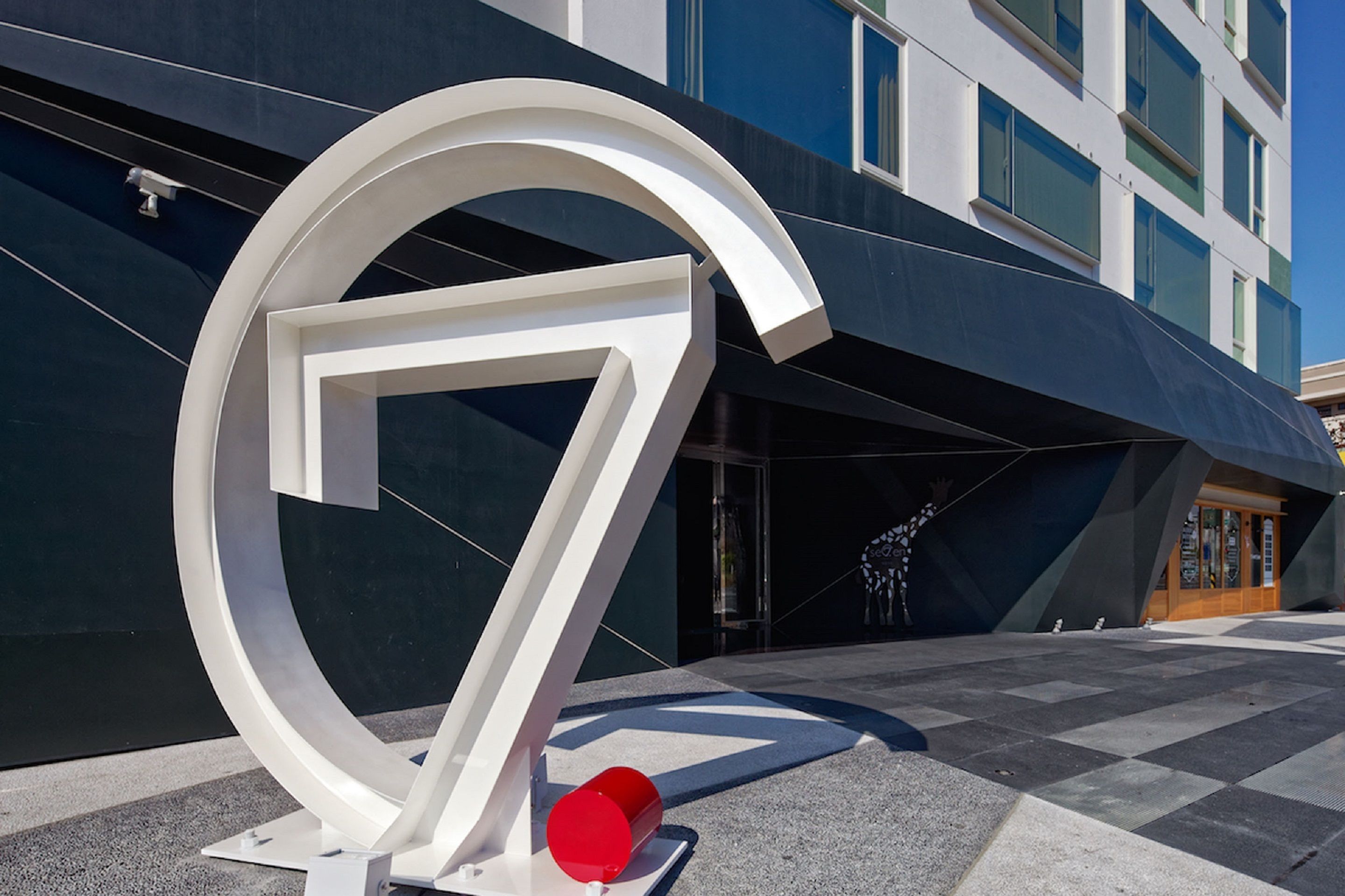 A modern building with a prominent white number '7' sculpture in front.