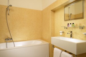 Un bagno con una vasca, un lavandino e uno specchio.