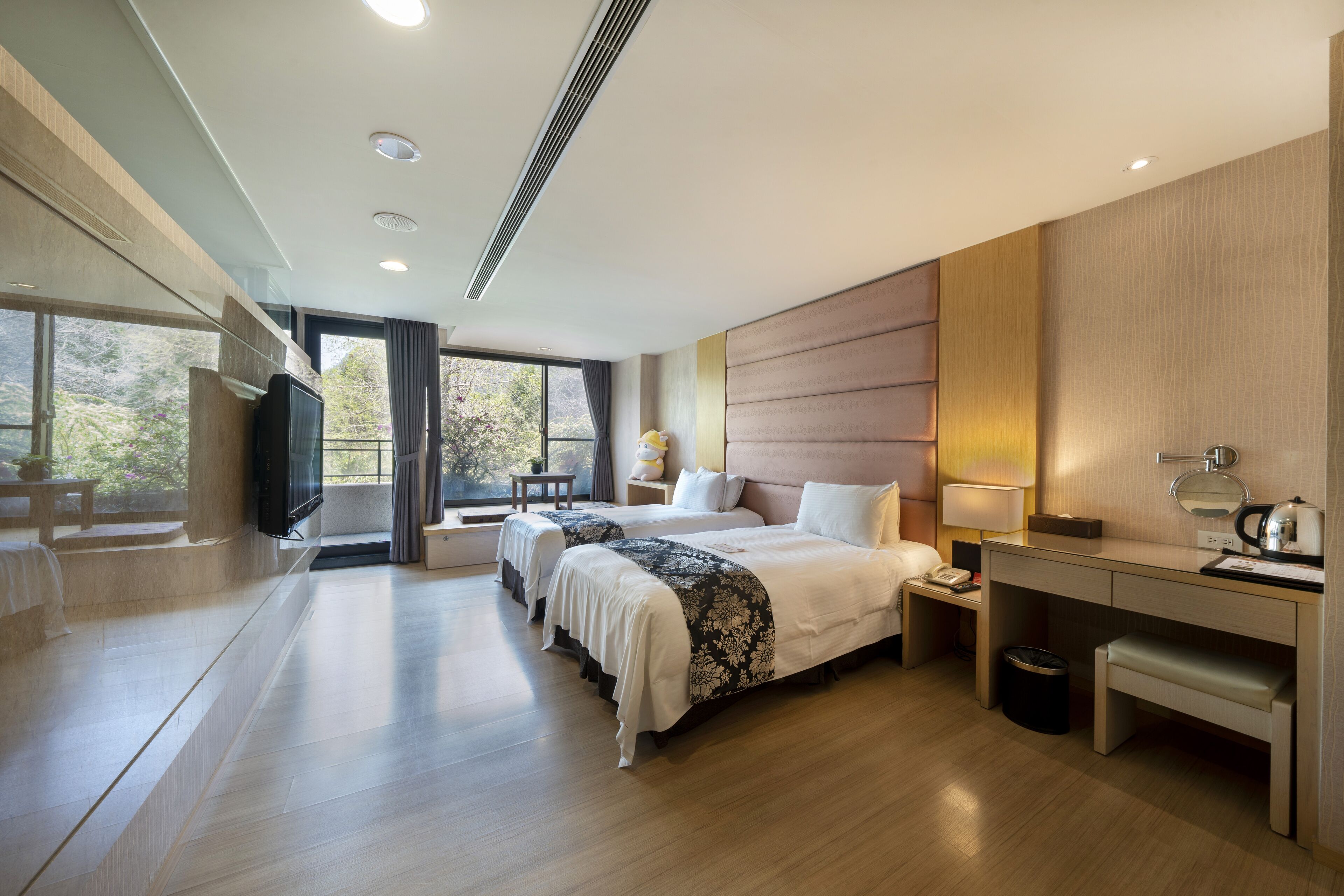 A modern hotel room with a large bed, a desk, a TV, and a view of the outdoors.