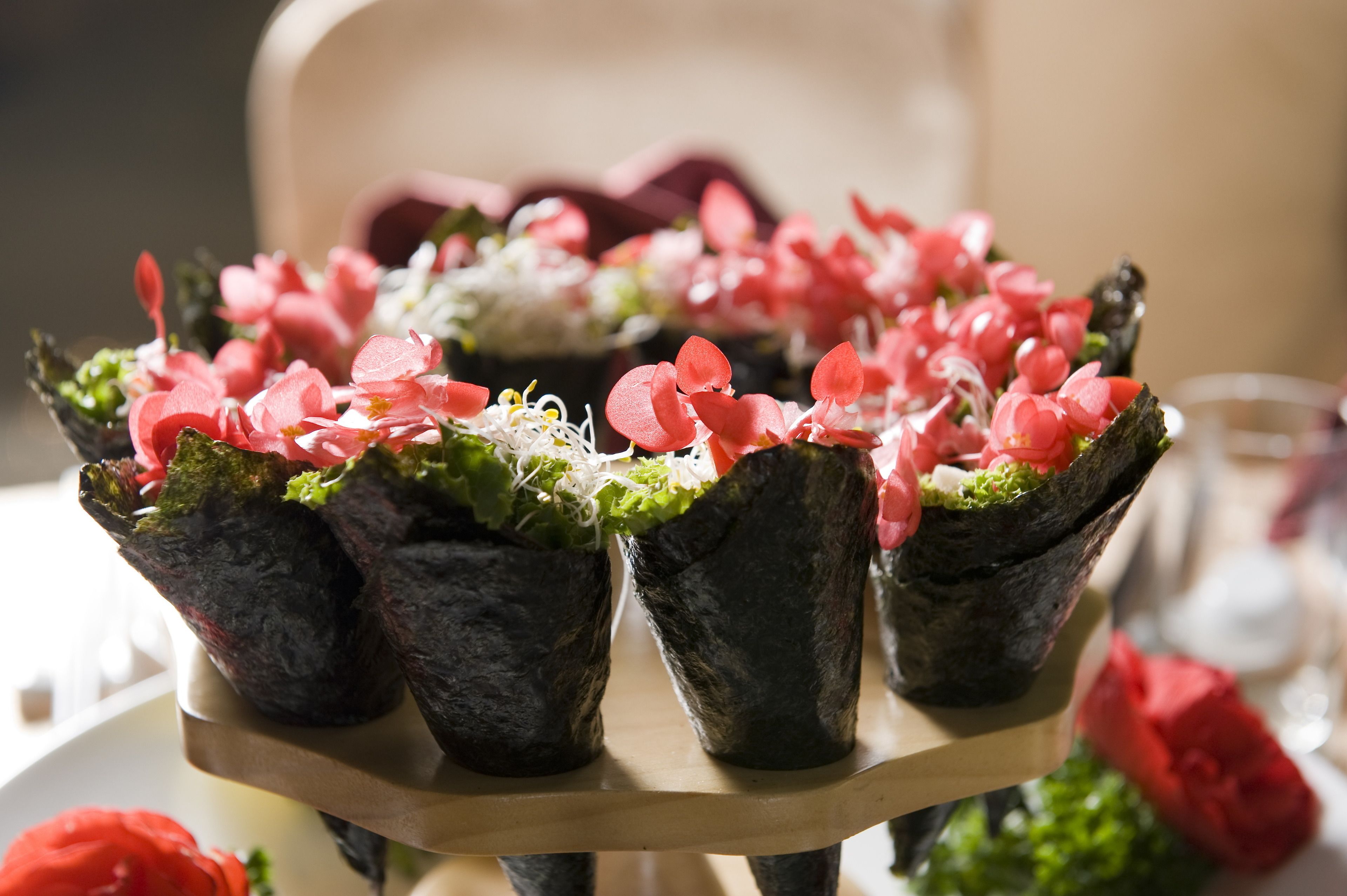 A tray of appetizers with leafy greens and pink flowers.