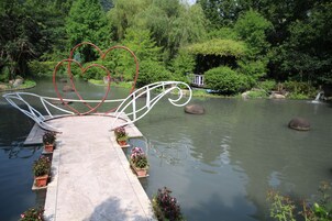 Un puente decorado con corazones sobre un río tranquilo, rodeado de vegetación exuberante y rocas.