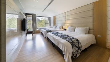 A modern hotel room with a large bed, two smaller beds, a TV, and a view of the outdoors.