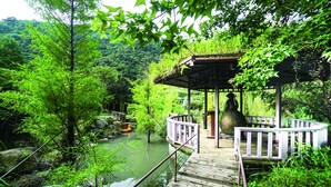 A wooden deck with a railing overlooking a river, surrounded by lush greenery and a gazebo. - Tai Yi Red Maple Resort (Puli)