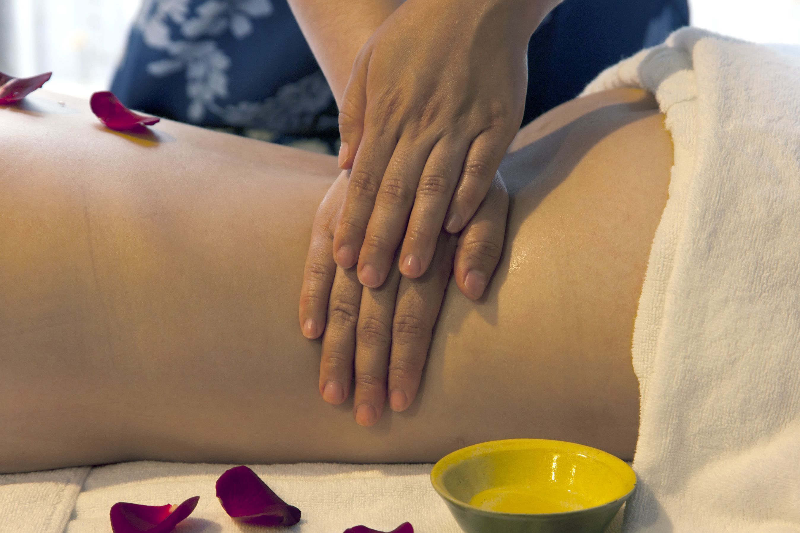 A massage session with a towel and a bowl of oil.
