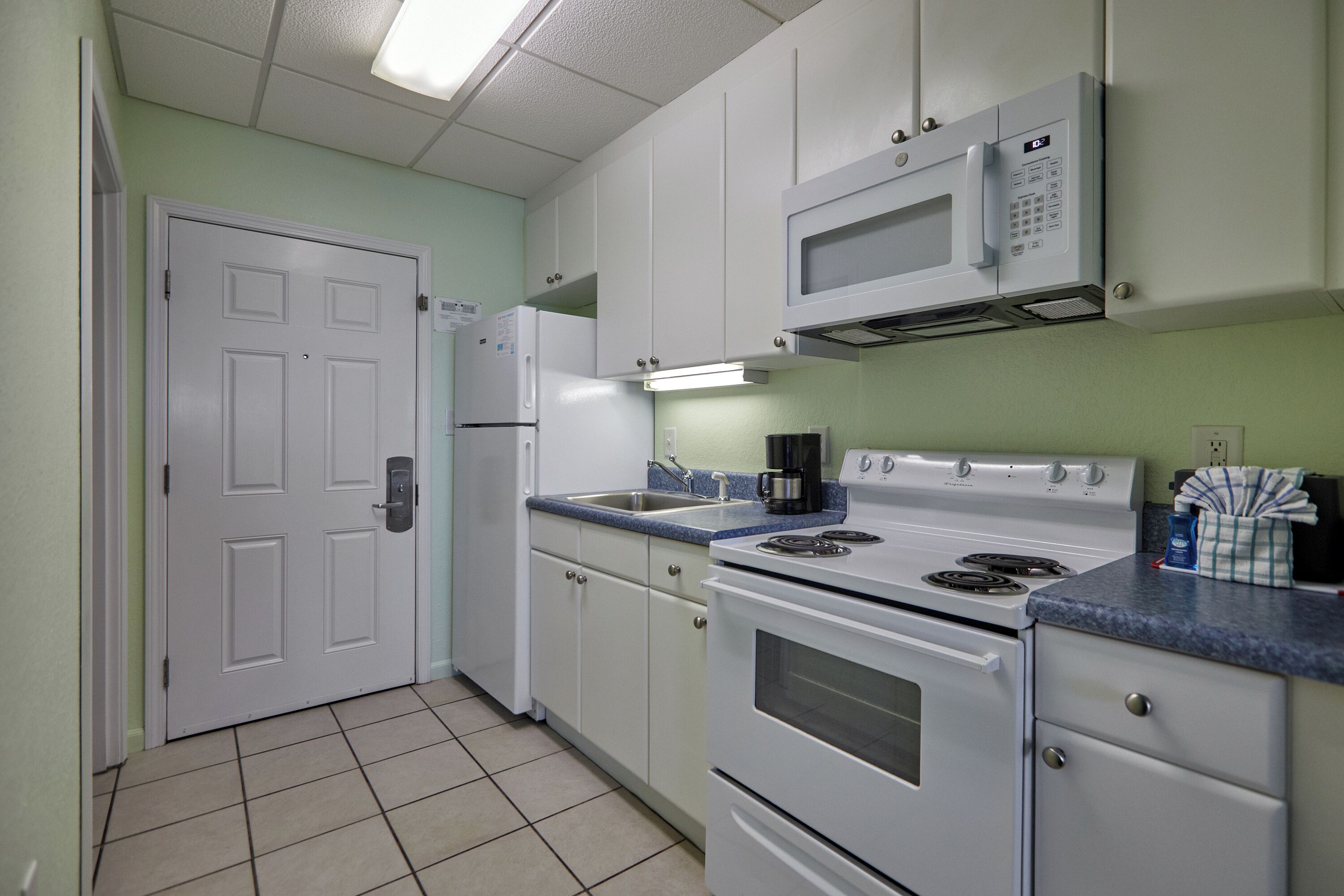 A kitchen with white cabinets, a microwave, a stove, and a refrigerator.