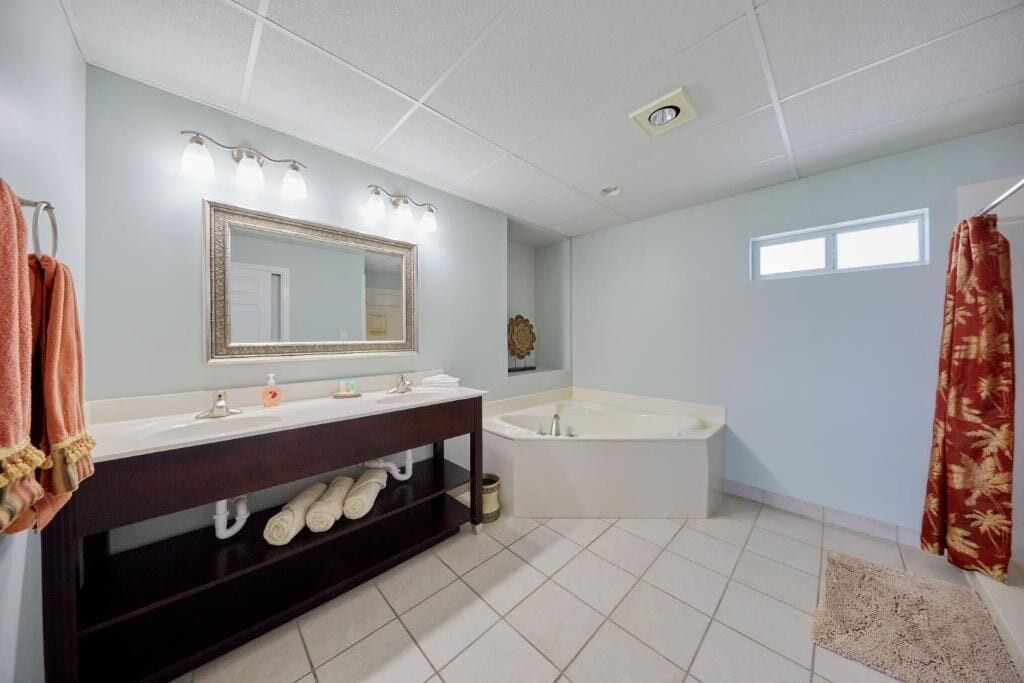 A bathroom with a double sink vanity, a large mirror, a bathtub, and a shower curtain.