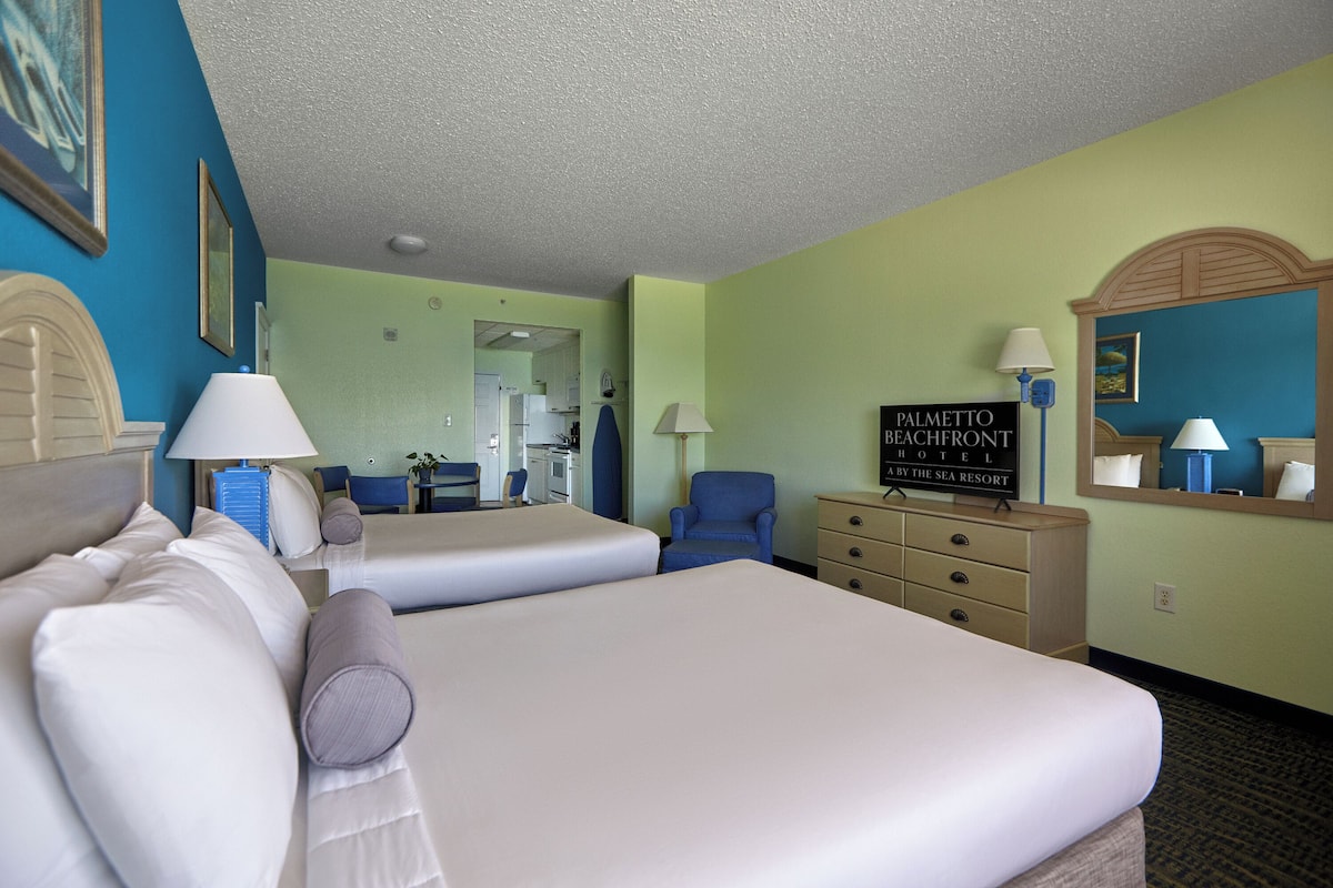 A hotel room with two beds, a desk, a chair, a dresser, and a sign indicating the hotel name.