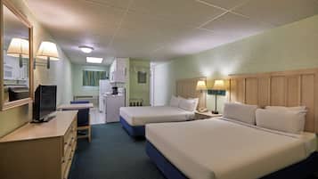 Een hotelkamer met twee bedden, een bureau, een televisie en een kitchenette.