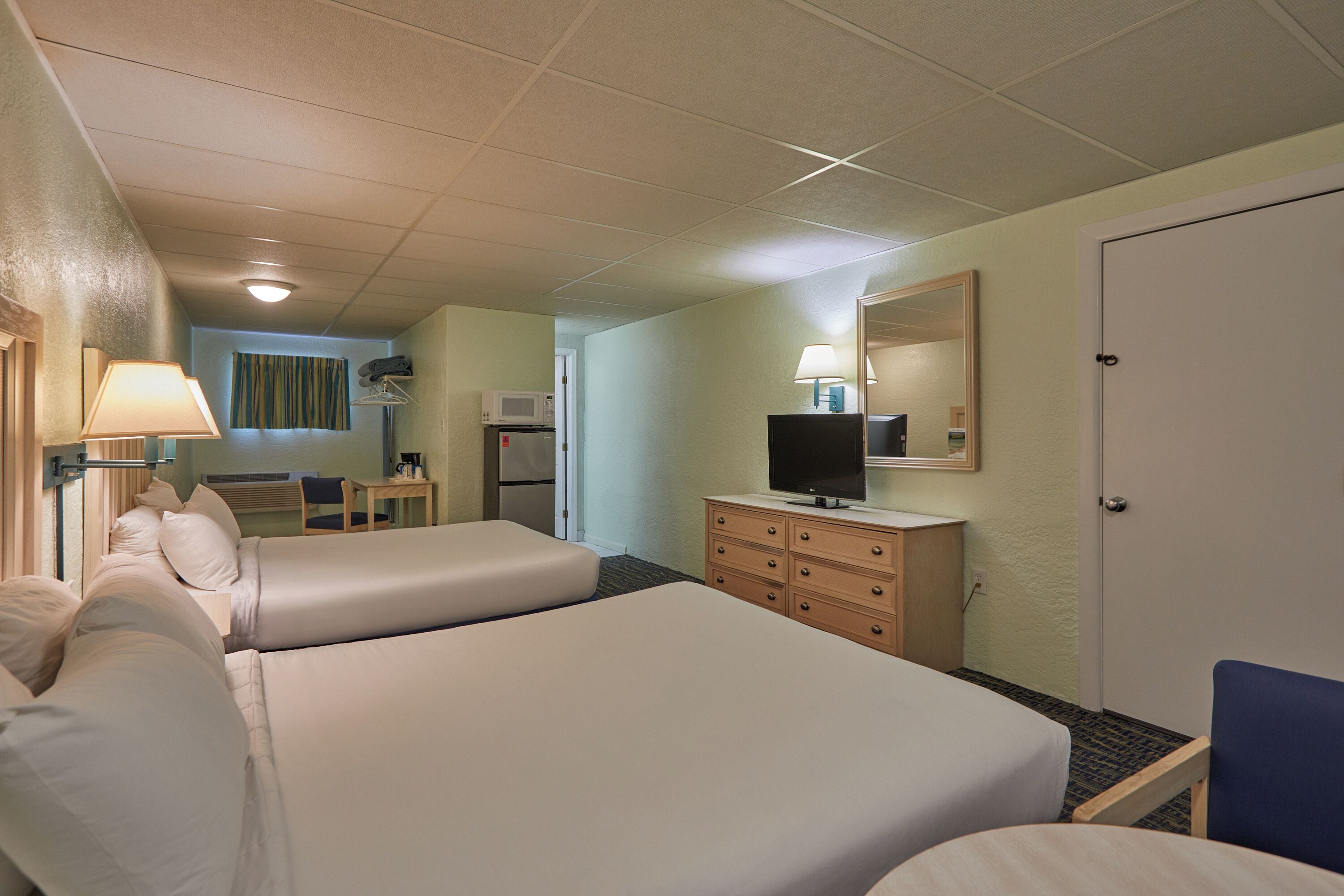Ett hotellrum med två sängar, en byrå, en tv, ett skrivbord och en stol.