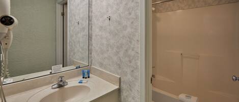 A bathroom with a sink, mirror, and a shower area.