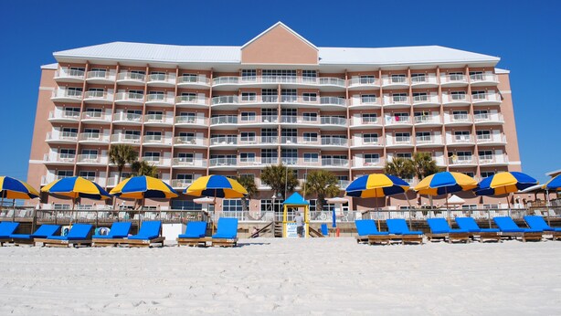 A multi-story hotel with balconies, beach umbrellas, and sun loungers.