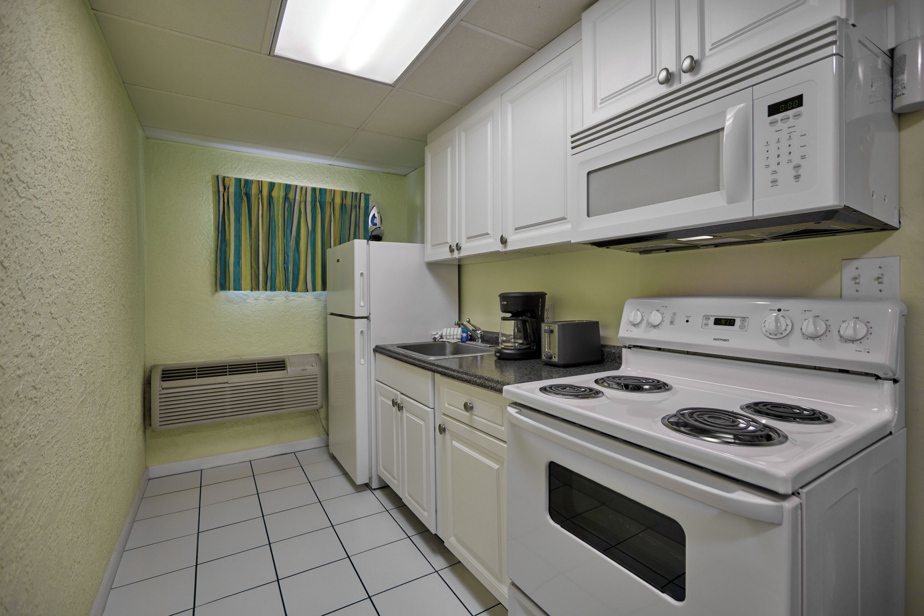 A kitchen with white cabinets, a microwave, a stove, and a refrigerator.