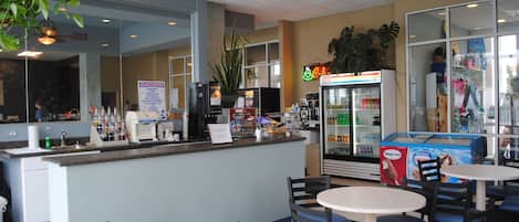 Un interior de restaurante con mostrador, zona de asientos y refrigerador.