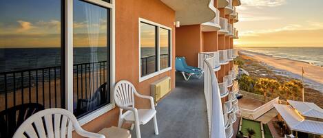 Un balcon avec vue sur l’océan, des chaises blanches et un petit espace piscine.