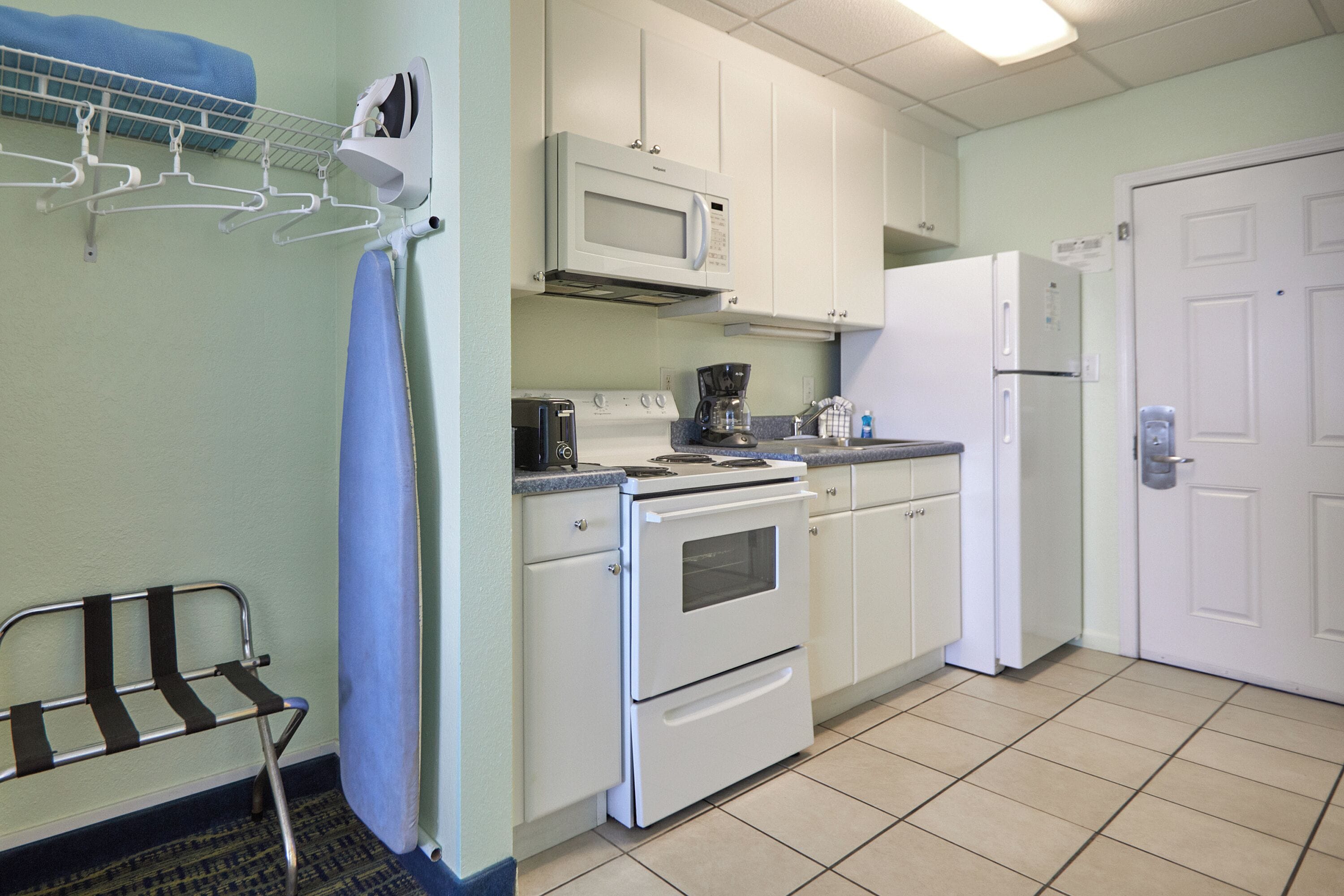 A kitchen with white cabinets, a microwave, a stove, and a refrigerator.