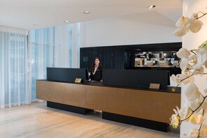 Un comptoir d’accueil moderne, avec une femme debout derrière.
