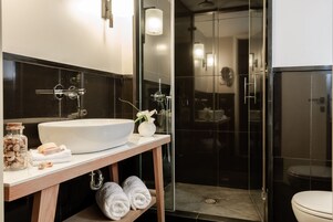 Un baño moderno con un lavamanos grande de color blanco, una cabina de ducha de vidrio y un inodoro.