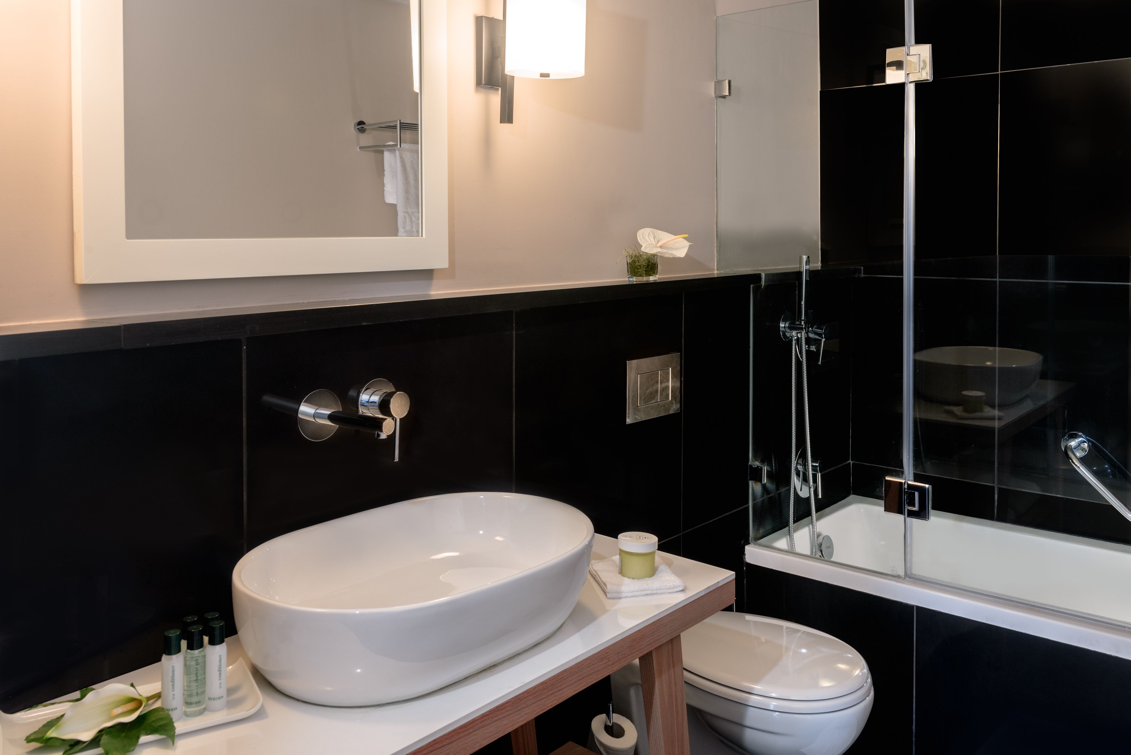 A modern bathroom with a large white sink, a toilet, and a glass-enclosed shower.