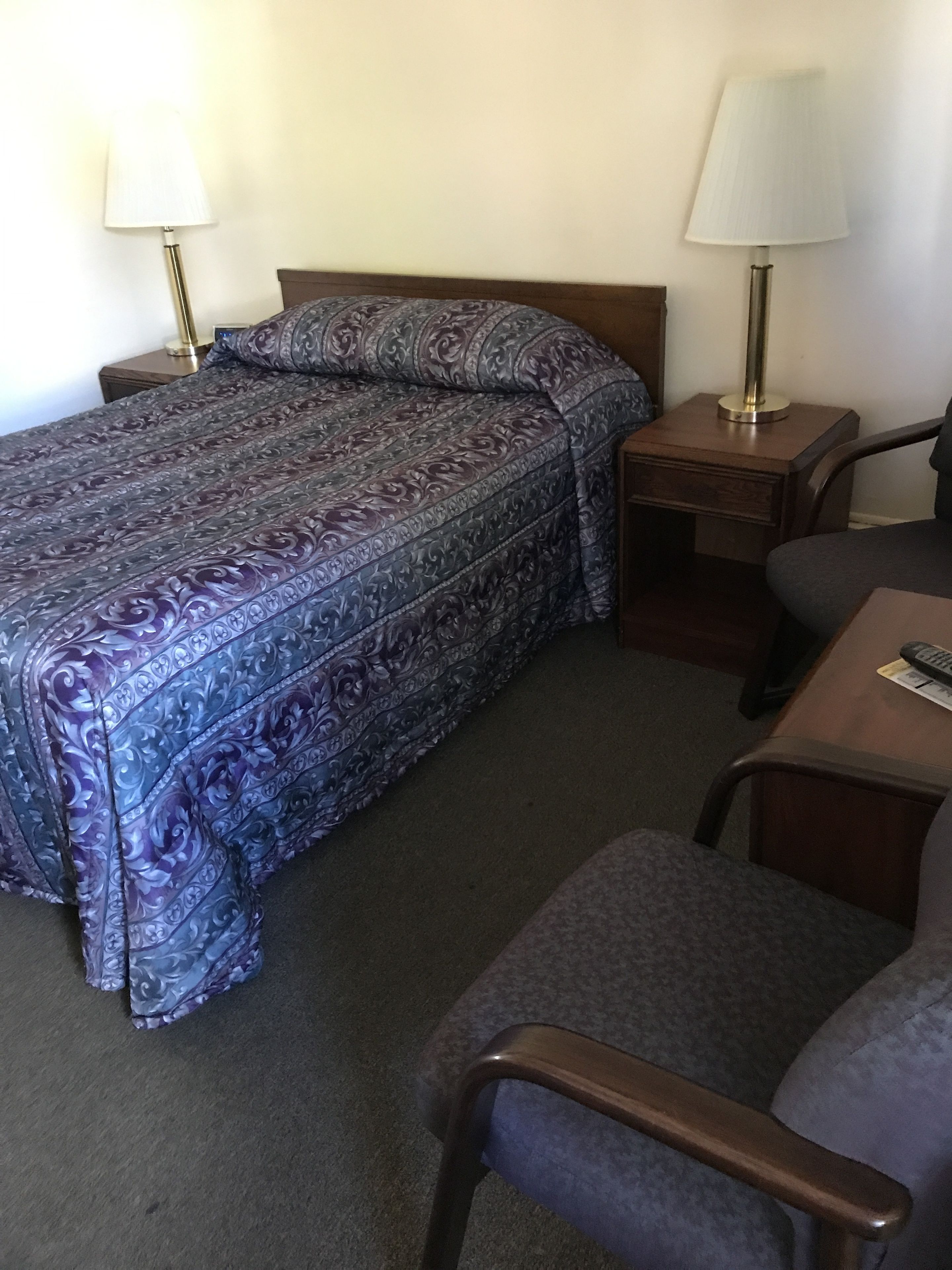 A hotel room with a bed, two bedside tables, a desk, and a chair.
