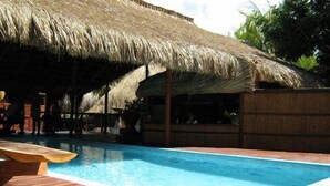 A pool area with a wooden deck and a thatched roof structure. - Casa Chibububo Lodge (Vilanculos)