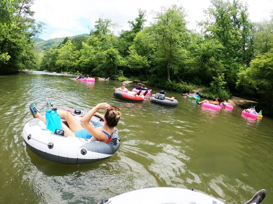 People floating on water in a river surrounded by greenery.