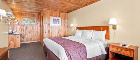 Un dormitorio con paneles de madera, una cama, lámparas de noche, una mesita de noche y un estante montado en la pared.