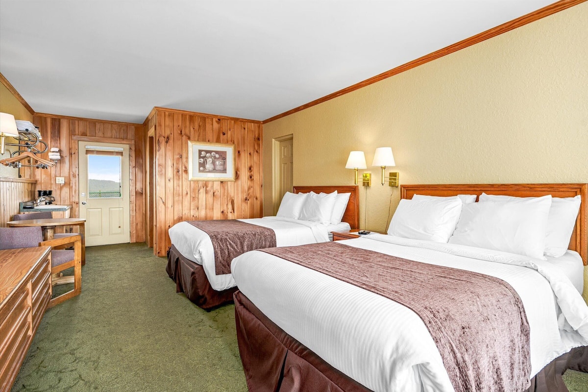 Quarto de hotel com duas camas, uma escrivaninha e uma cadeira.