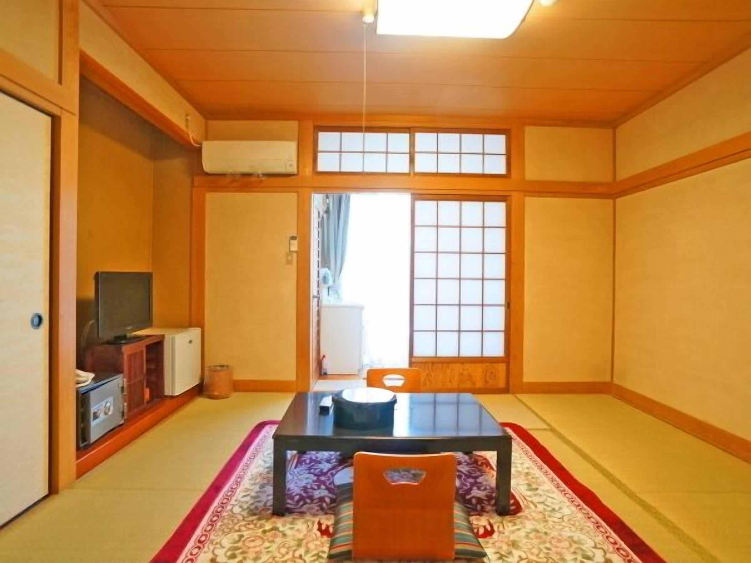 A traditional Japanese-style room with tatami flooring, a low table, and a sliding door.